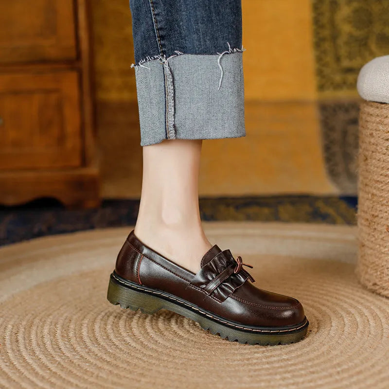 Black women's leather shoes with chunky flat heel, round toe, and low-top design on a plain background.