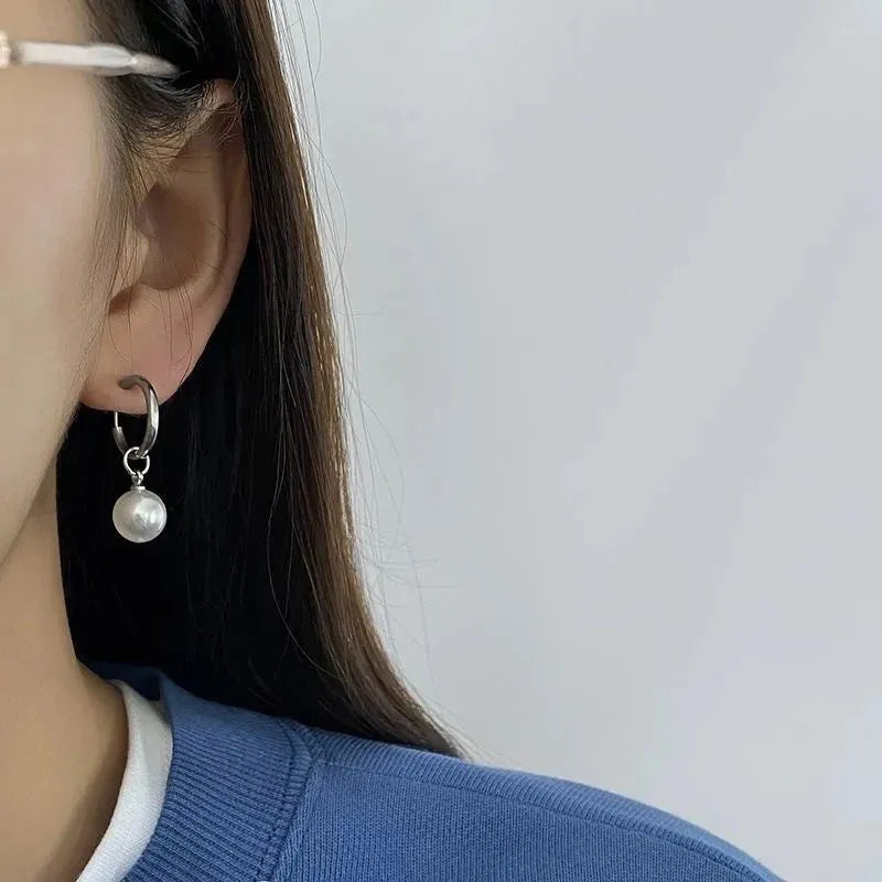 A pair of women's geometric pearl hoop earrings with alloy construction and titanium steel posts.