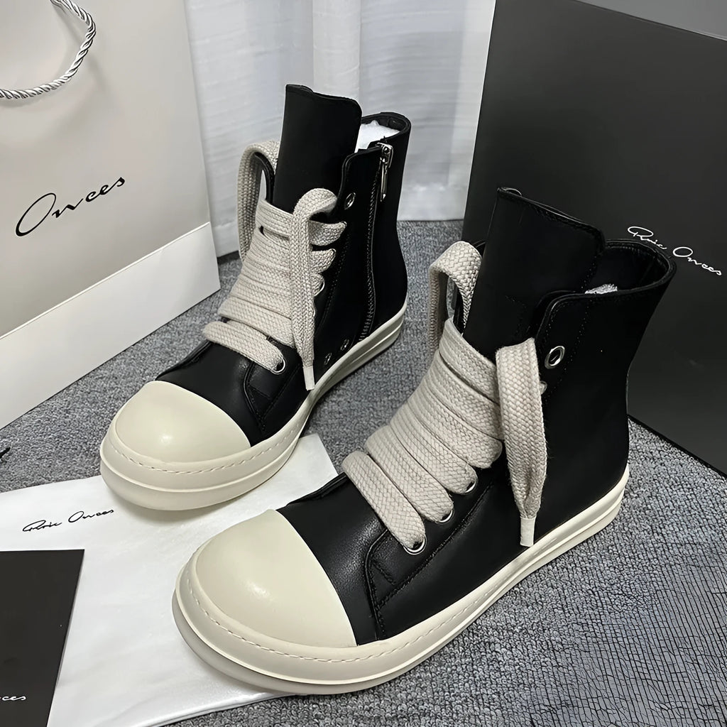 Black high-top leather sneakers with side zipper on a white background.