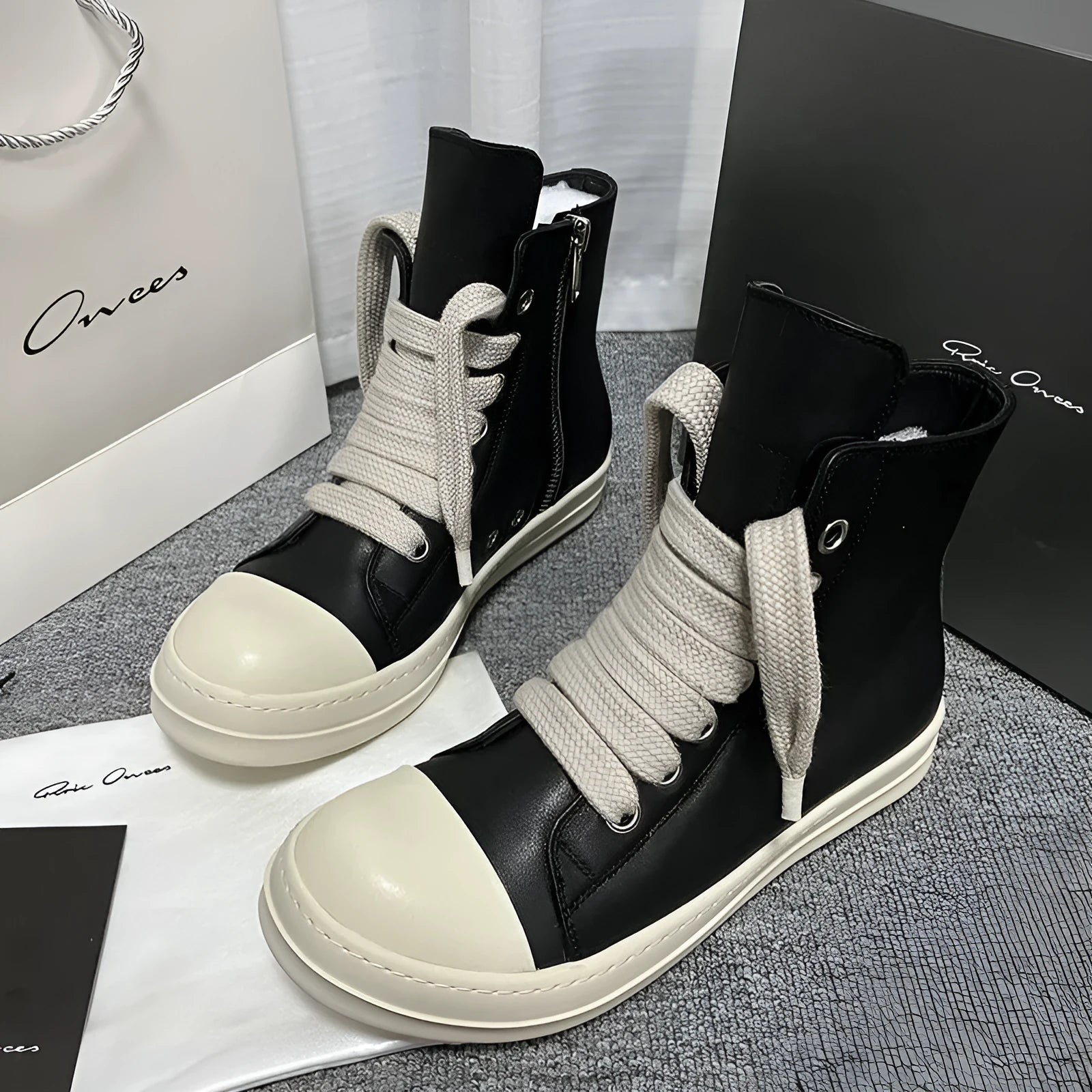 Black high-top leather sneakers with side zipper on a white background.