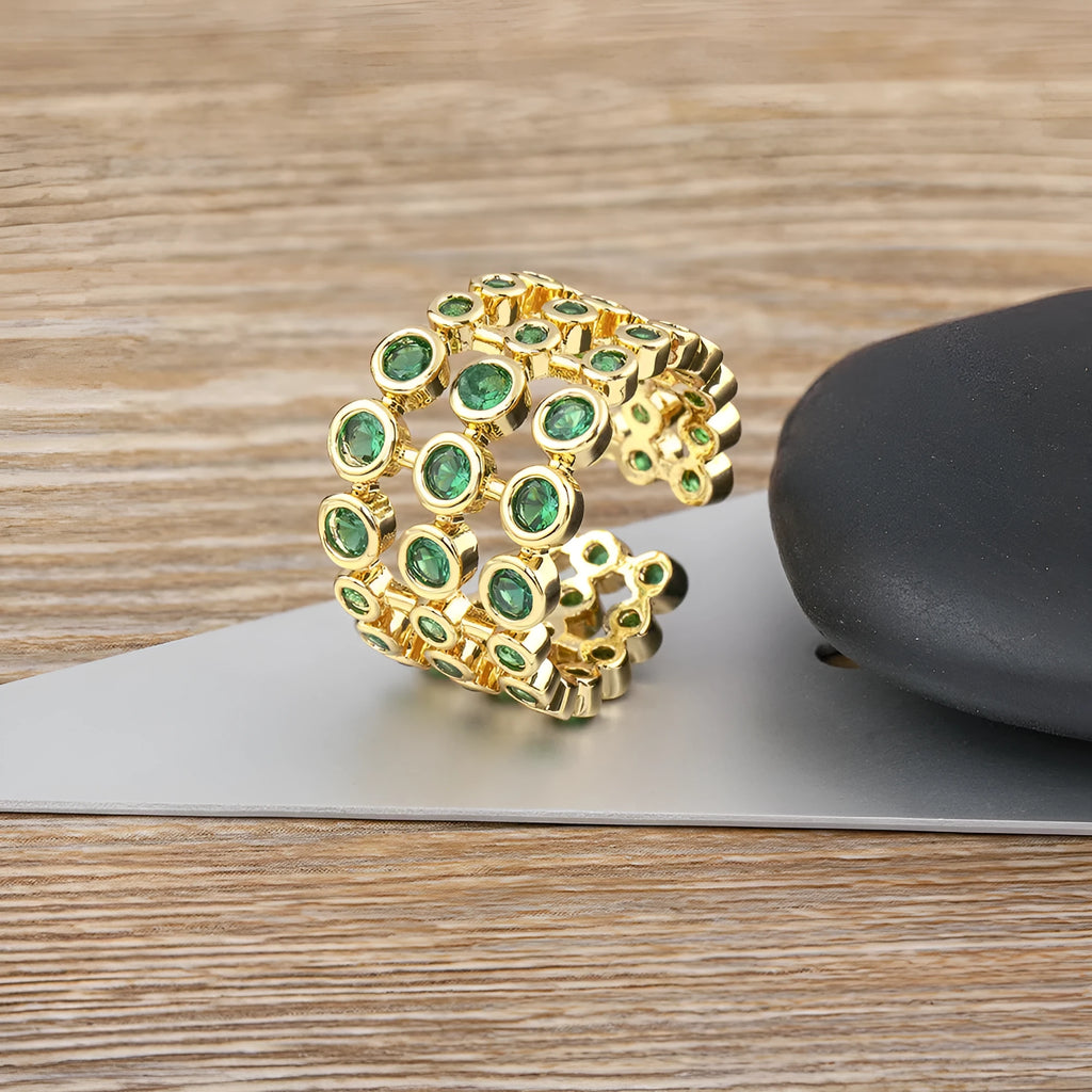 Close-up of a wide gold-plated ring with a large emerald-cut green zircon stone in a three-layer unisex design.