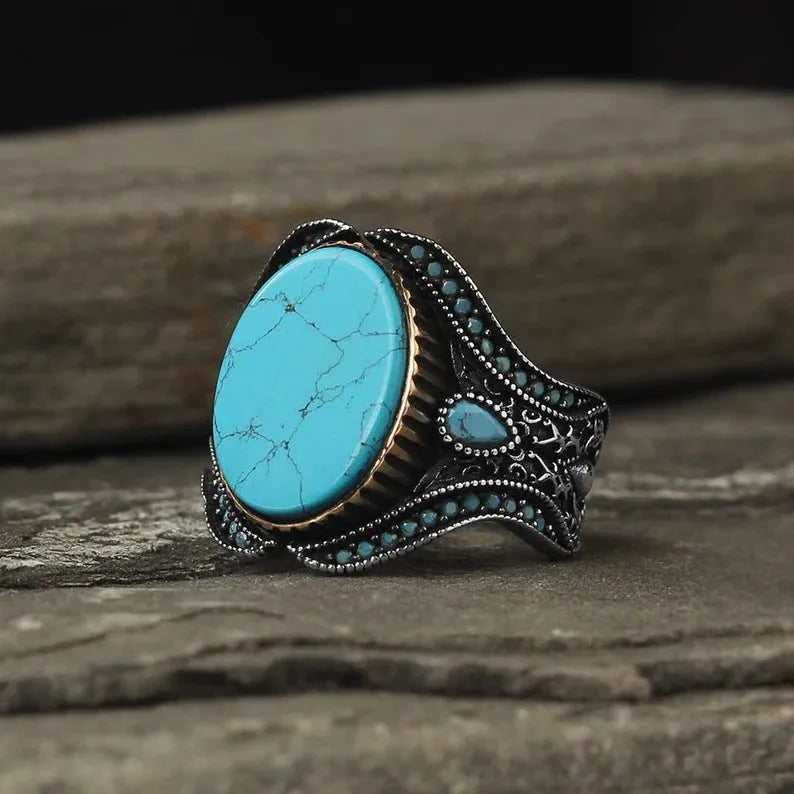 Men's antique silver alloy ring with a round turquoise-coloured centre on a grey background.