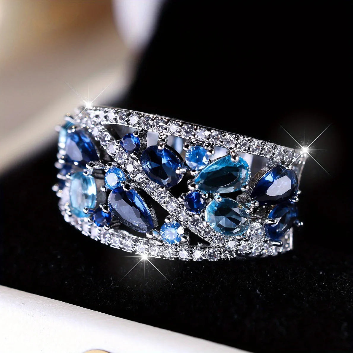 Women's round hollow fashion ring with gemstone accents on a copper band, shown in gold and platinum finishes.