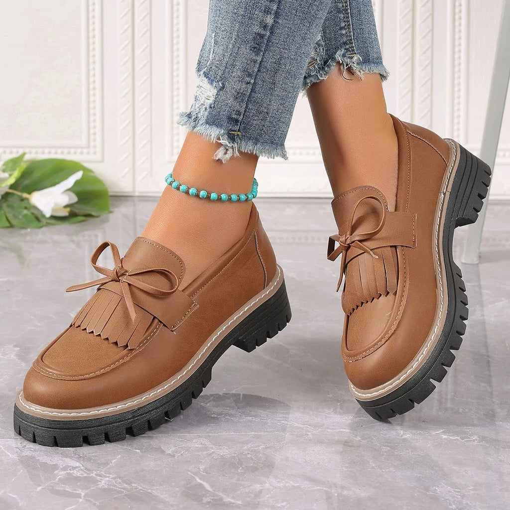 Black plus size women's loafers with tassel and bow knot decoration on a chunky low heel.