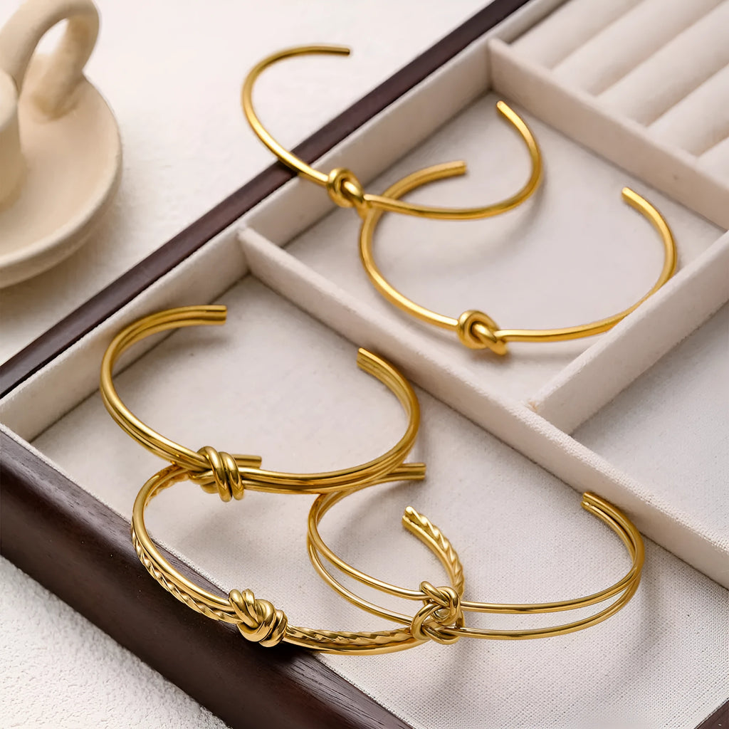 Open C-shaped stainless steel bracelet with knotted double layer design in gold or silver finish.