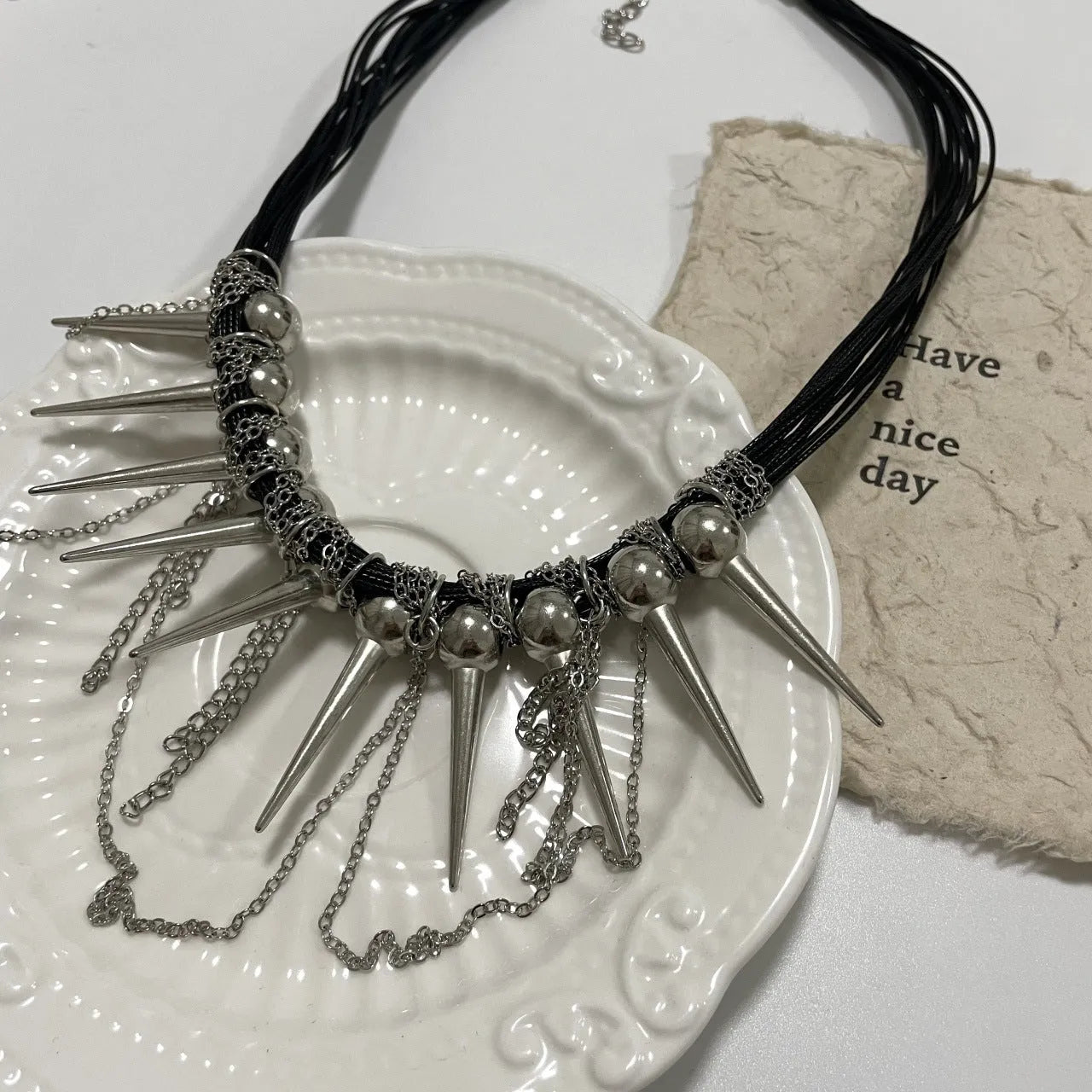 Women's leather necklace with electroplated finish showing rivet decoration and winding tassel design with round beads