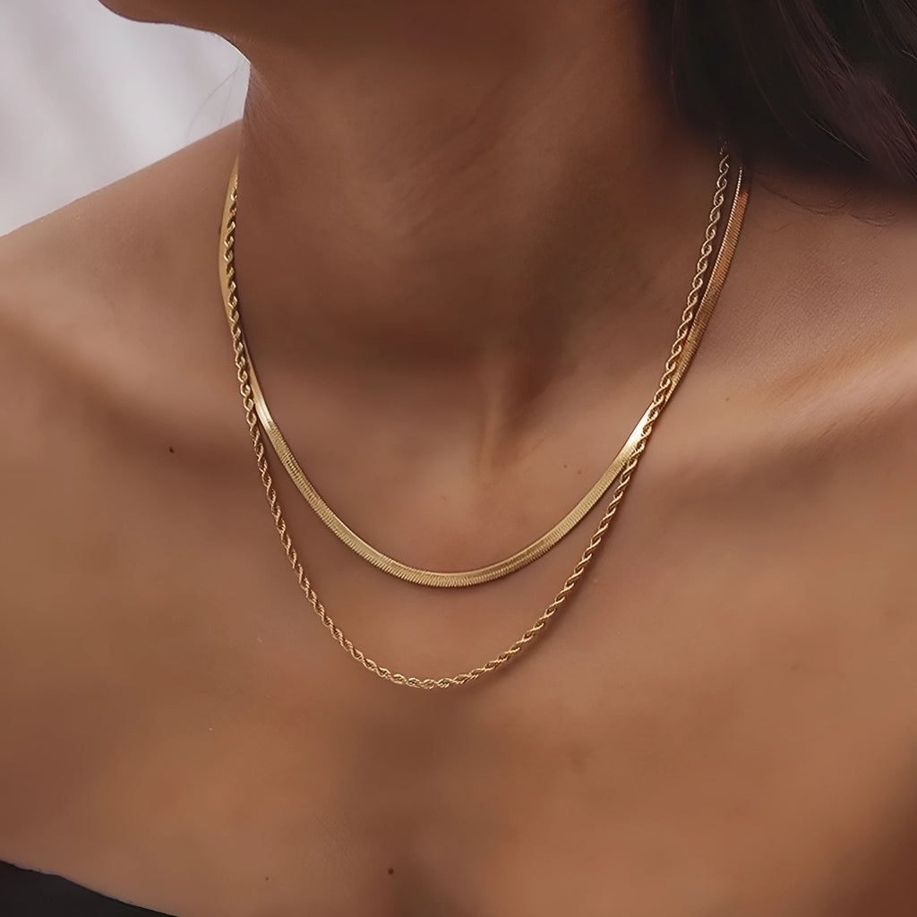 Close-up of a geometric double-layer twist pendant necklace on a textured snake bones chain.