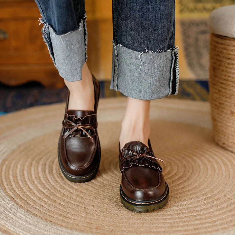 Black women's leather shoes with chunky flat heel, round toe, and low-top design on a plain background.
