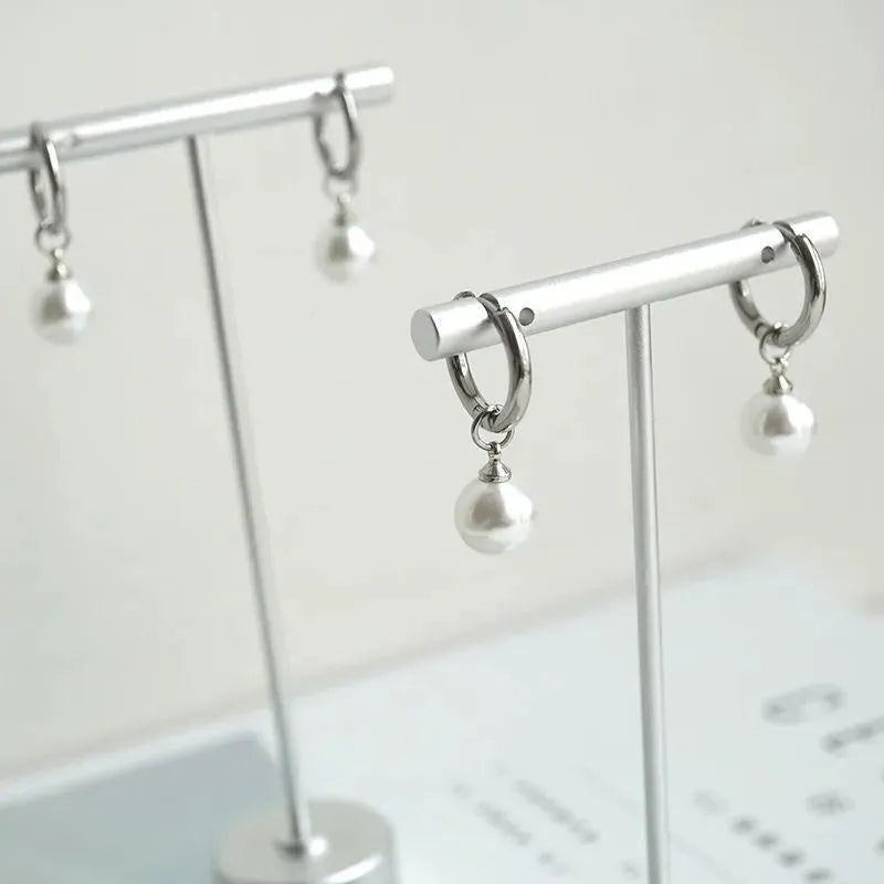 A pair of women's geometric pearl hoop earrings with alloy construction and titanium steel posts.