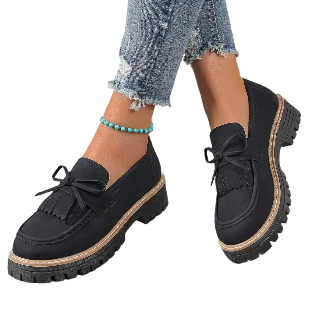Black plus size women's loafers with tassel and bow knot decoration on a chunky low heel.
