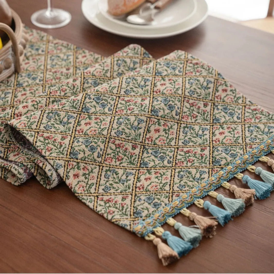 Dark blue Nordic Jacquard table runner with bouquet design and tassels laid on a wooden table.