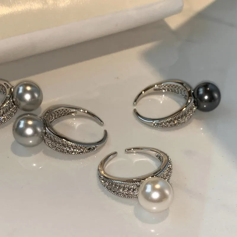 Copper geometric open ring with black pearl on a model's finger, showing adjustable gap.