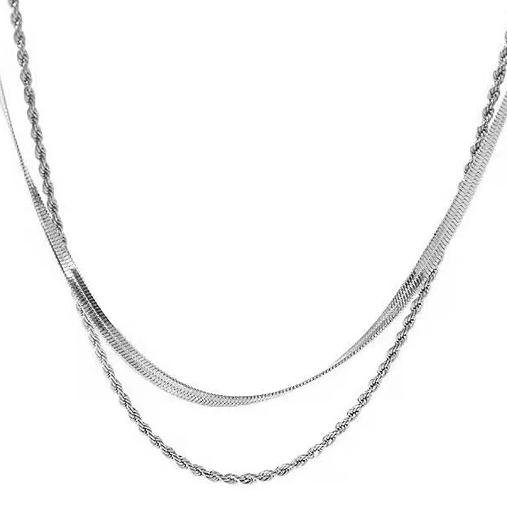 Close-up of a geometric double-layer twist pendant necklace on a textured snake bones chain.