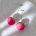 Acrylic peach-shaped dangle earrings with copper findings, shown in small and large size variations.
