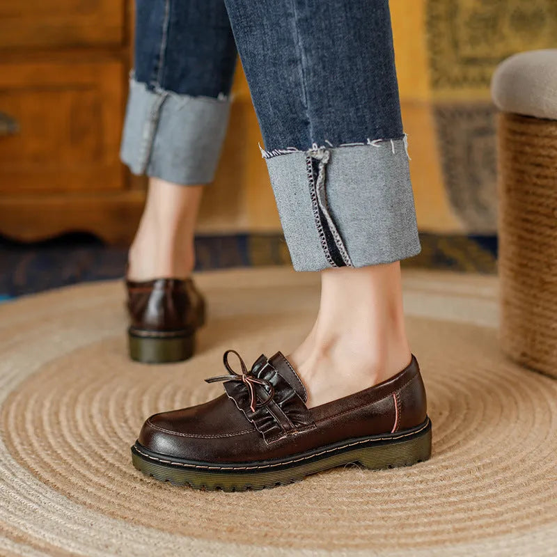 Black women's leather shoes with chunky flat heel, round toe, and low-top design on a plain background.