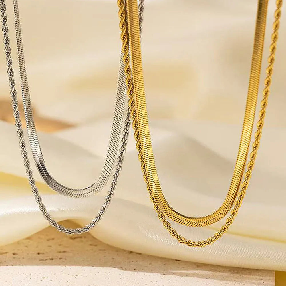 Close-up of a geometric double-layer twist pendant necklace on a textured snake bones chain.