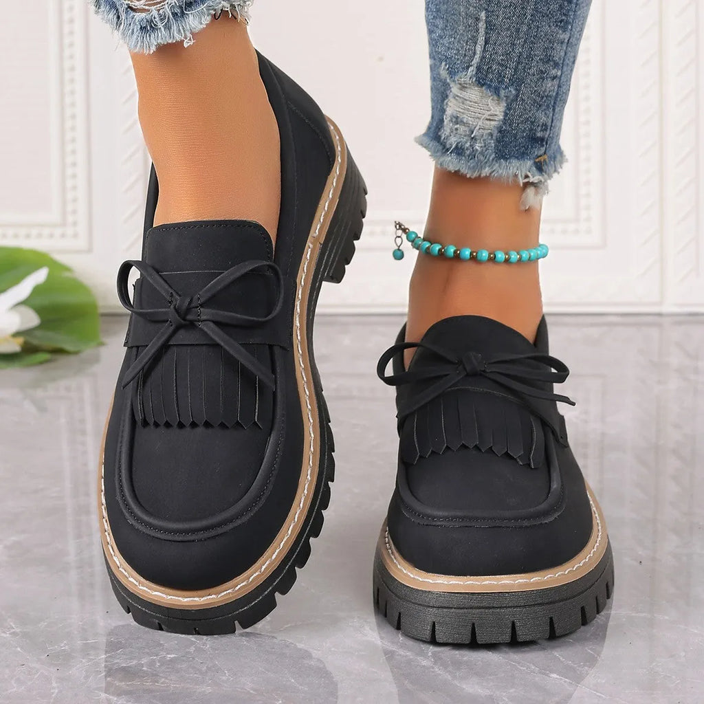 Black plus size women's loafers with tassel and bow knot decoration on a chunky low heel.