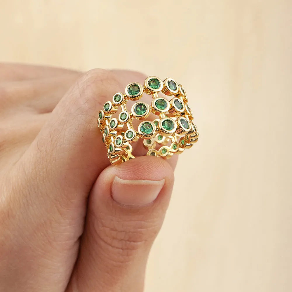 Close-up of a wide gold-plated ring with a large emerald-cut green zircon stone in a three-layer unisex design.