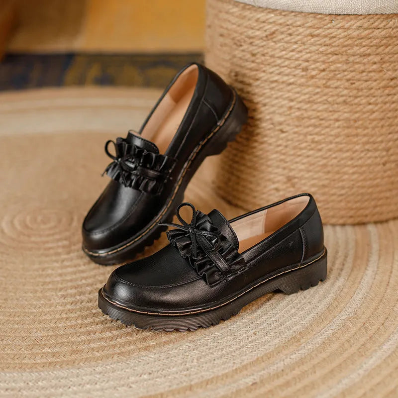 Black women's leather shoes with chunky flat heel, round toe, and low-top design on a plain background.
