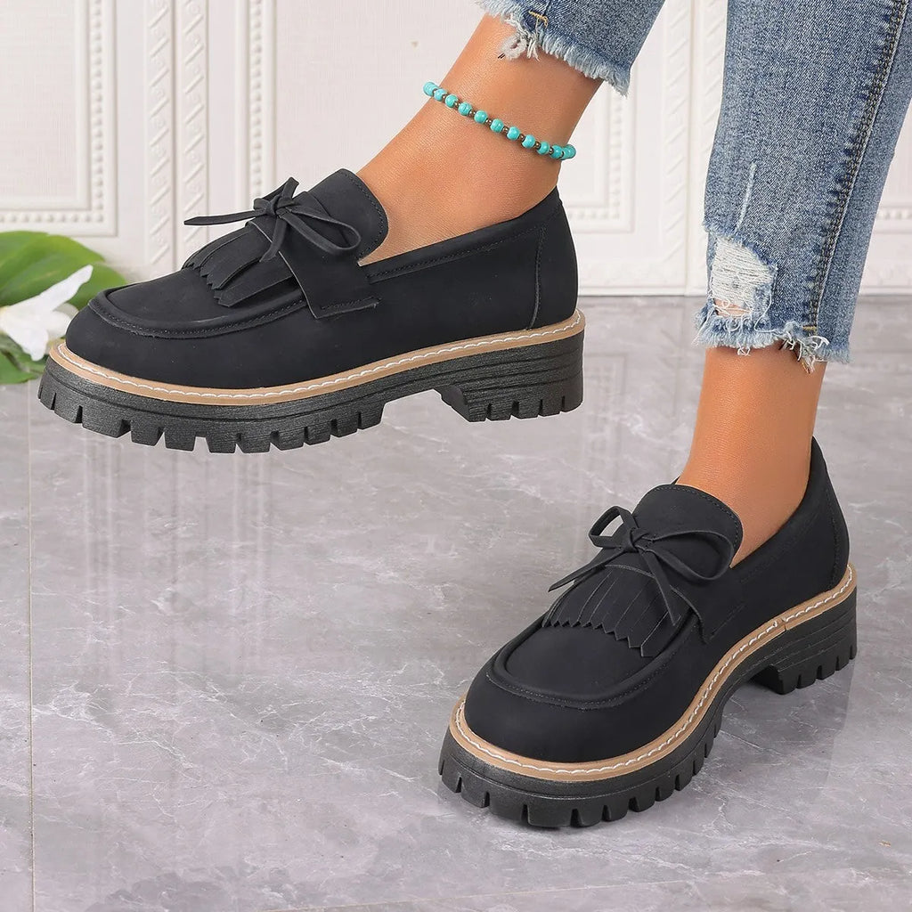 Black plus size women's loafers with tassel and bow knot decoration on a chunky low heel.