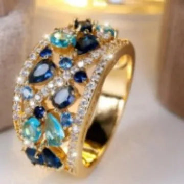 Women's round hollow fashion ring with gemstone accents on a copper band, shown in gold and platinum finishes.