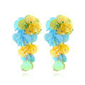 Handmade exaggerated floral earrings with colourful string beads and leaves on a purple background.