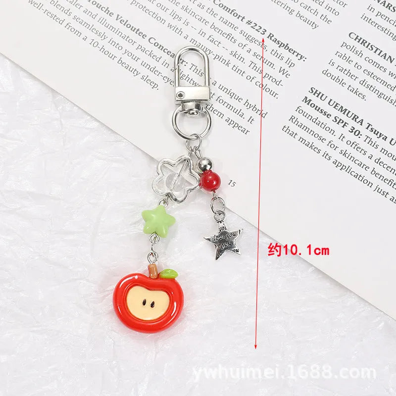 Plastic resin fruit charm keychain with removable rope in strawberry, green apple, and red apple designs.