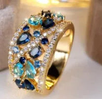 Women's round hollow fashion ring with gemstone accents on a copper band, shown in gold and platinum finishes.