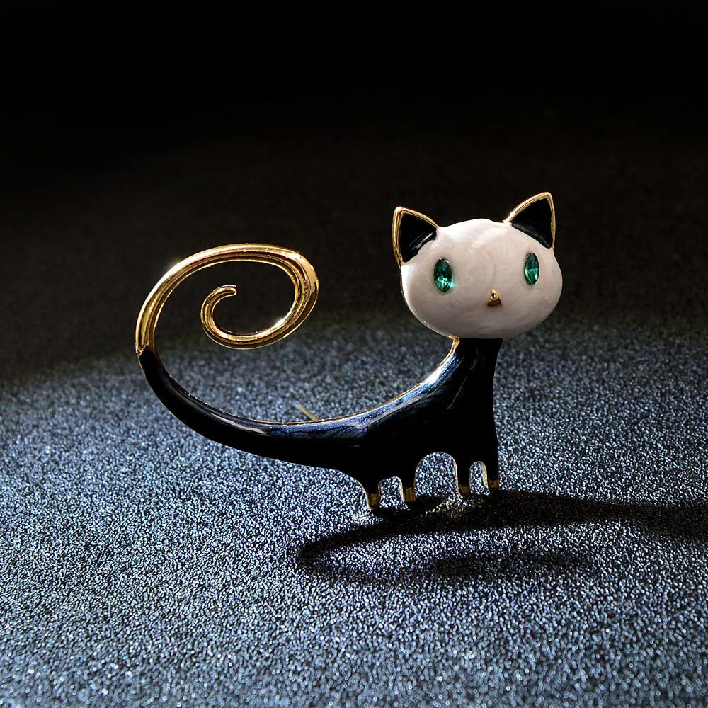 Orange and white alloy brooch with painted design of a cat with its tail up.