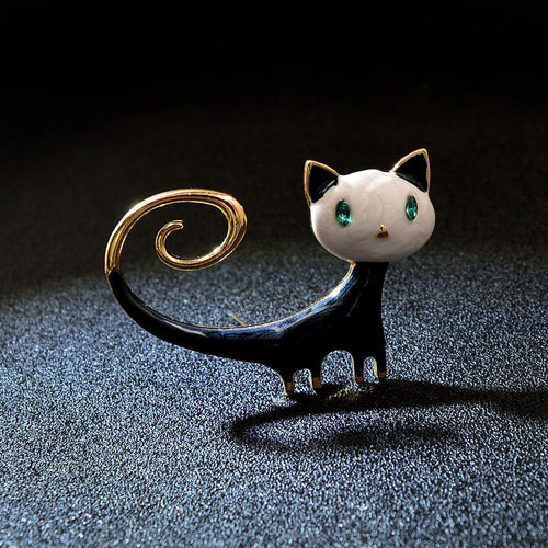 Orange and white alloy brooch with painted design of a cat with its tail up.