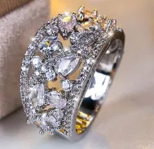 Women's round hollow fashion ring with gemstone accents on a copper band, shown in gold and platinum finishes.