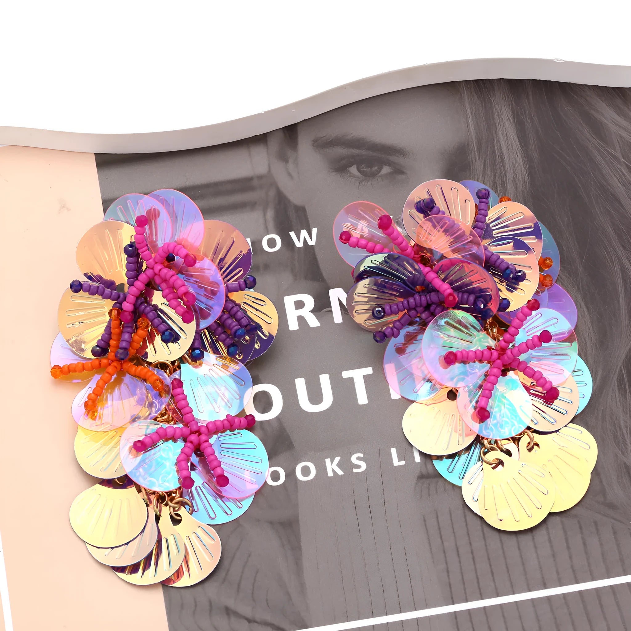 Handmade exaggerated floral earrings with colourful string beads and leaves on a purple background.