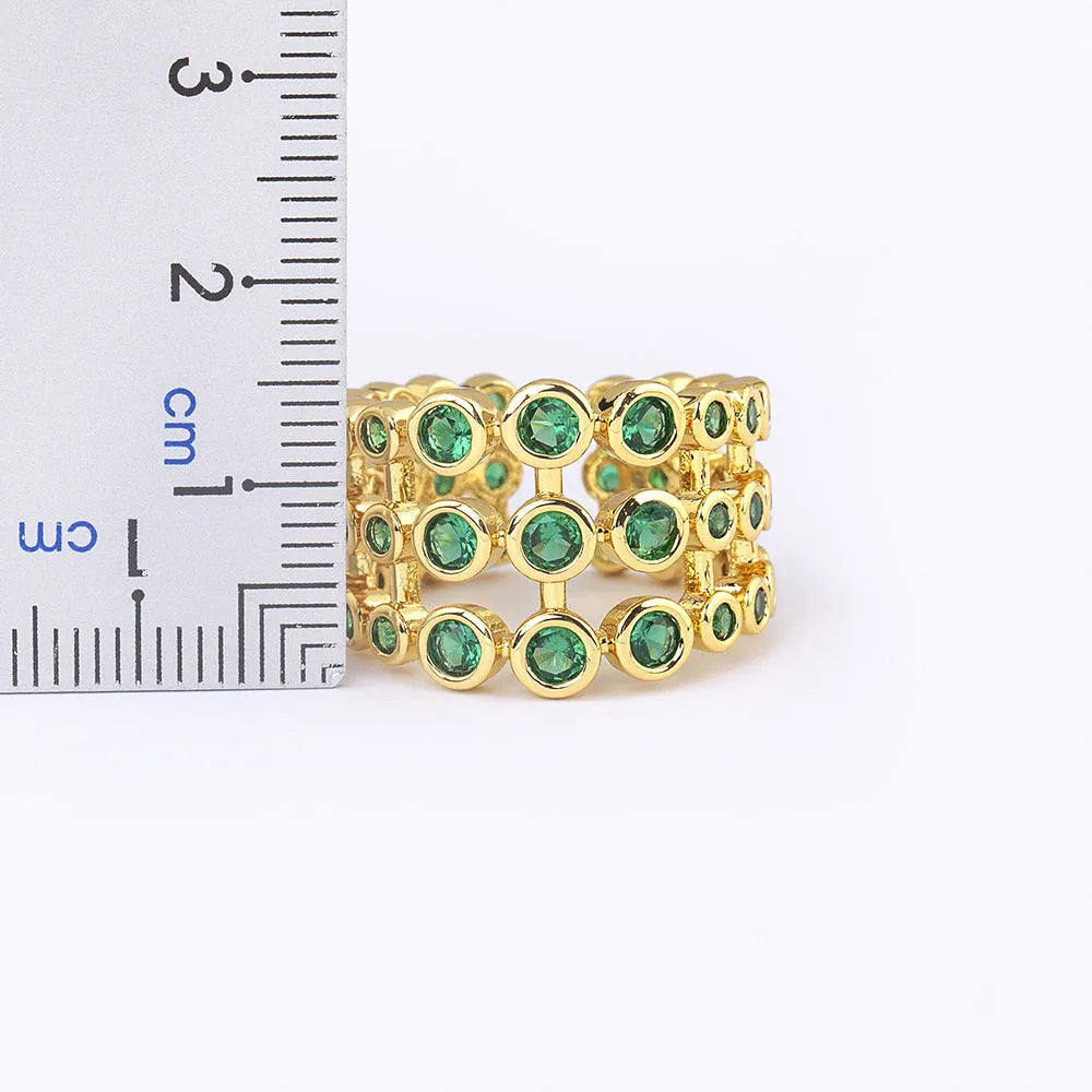 Close-up of a wide gold-plated ring with a large emerald-cut green zircon stone in a three-layer unisex design.