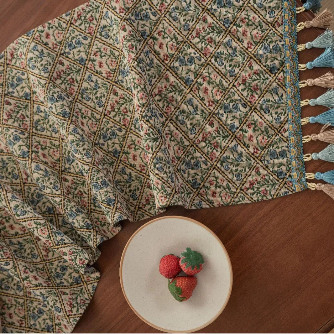 Dark blue Nordic Jacquard table runner with bouquet design and tassels laid on a wooden table.