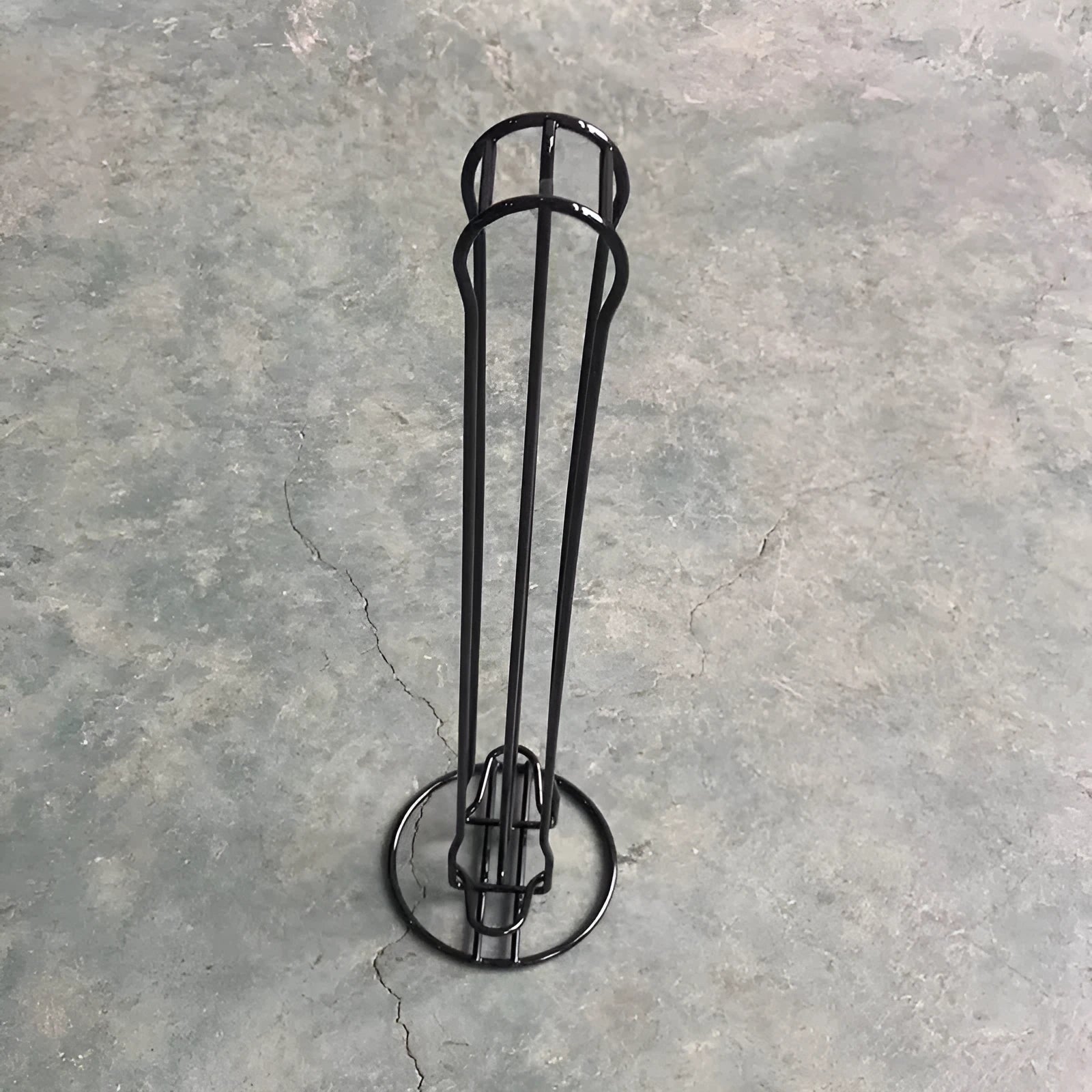 Black iron coffee capsule storage rack holding multiple pods on display shelves.
