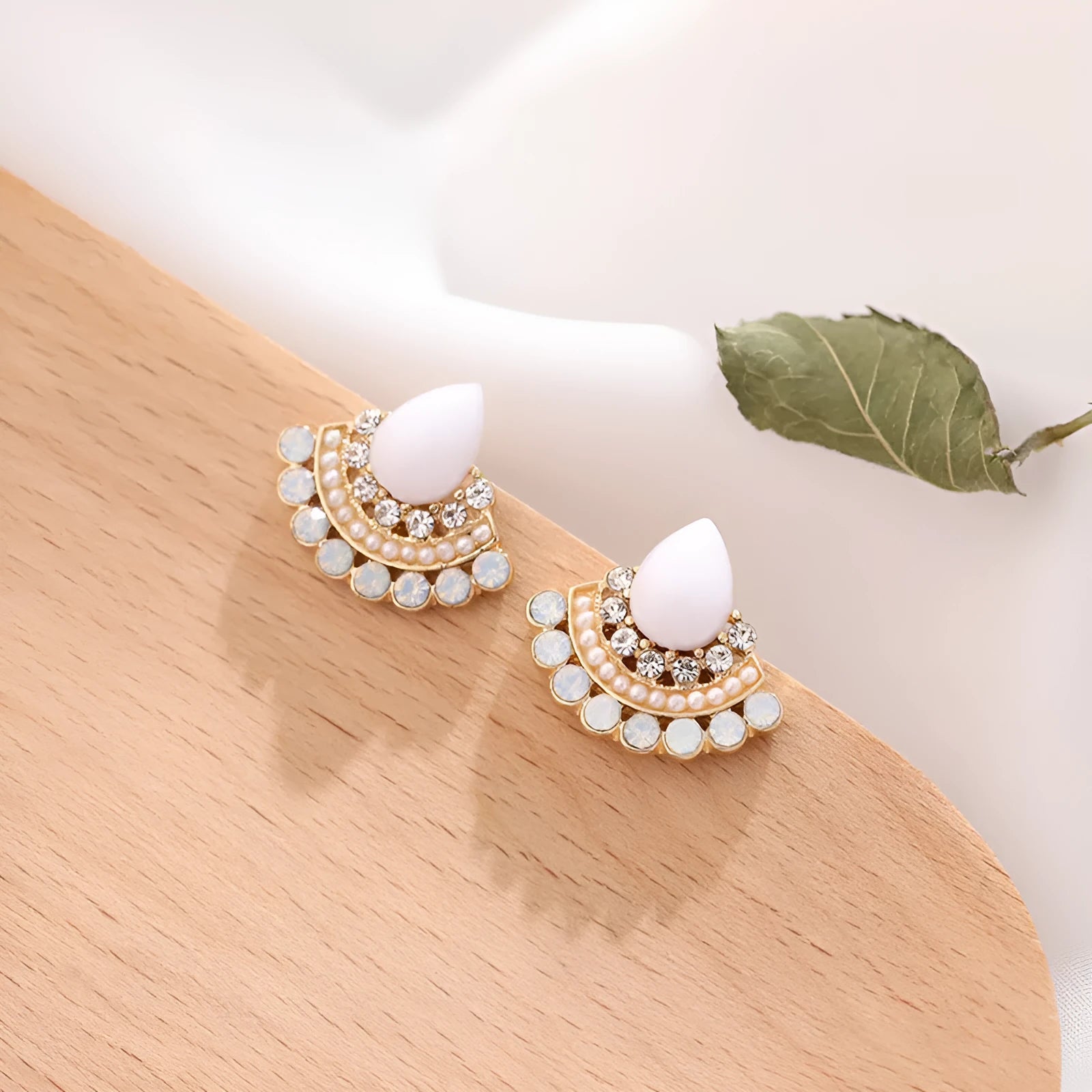 Silver fan-shaped drop earrings with rhinestone and opal geometric design on white background