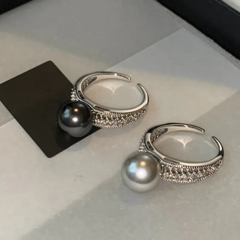 Copper geometric open ring with black pearl on a model's finger, showing adjustable gap.