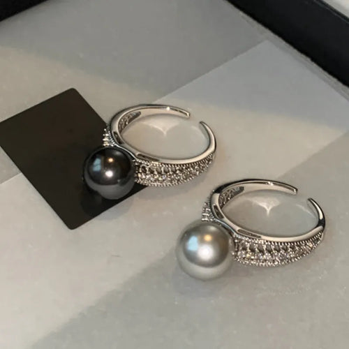 Copper geometric open ring with black pearl on a model's finger, showing adjustable gap.
