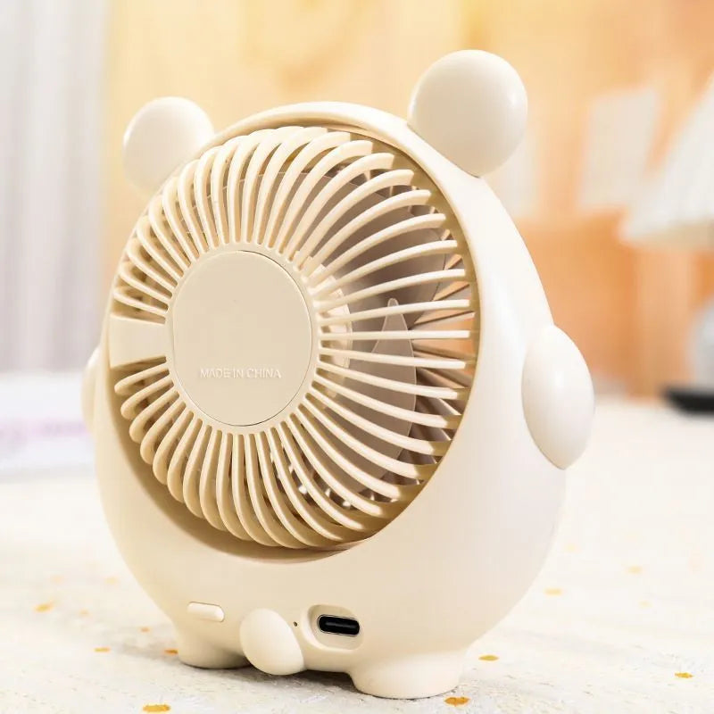 USB desktop electric fan in one of six colours including bear brown and puppy designs on a desk.