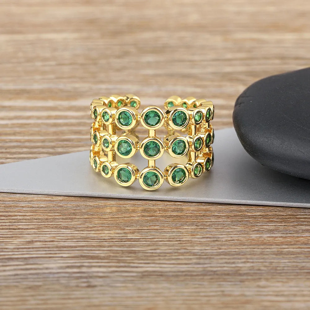 Close-up of a wide gold-plated ring with a large emerald-cut green zircon stone in a three-layer unisex design.