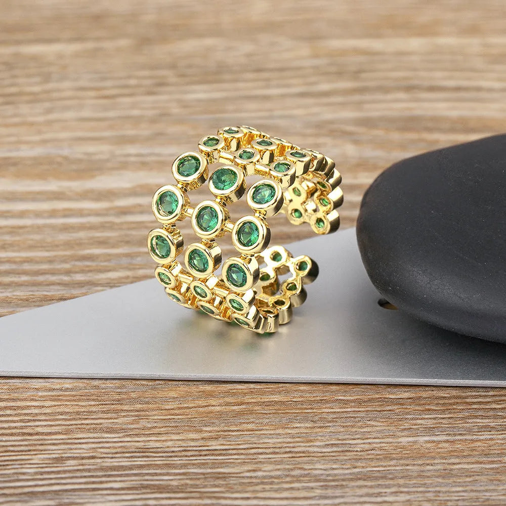 Close-up of a wide gold-plated ring with a large emerald-cut green zircon stone in a three-layer unisex design.