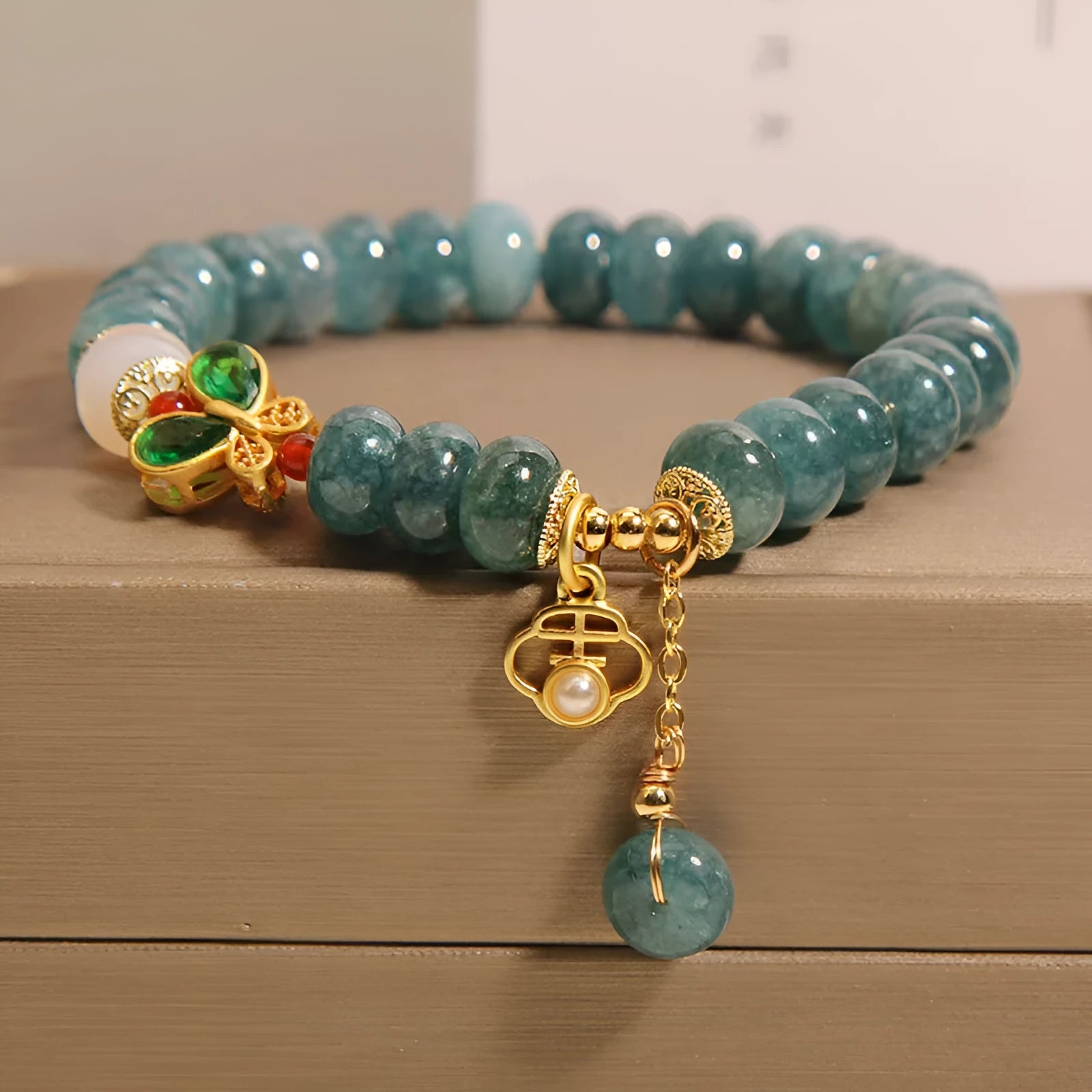 Blue water jade abacus bead bracelet with butterfly charm and white agate on an alloy band.