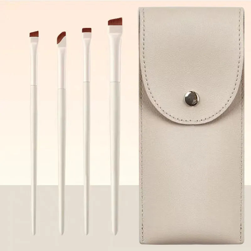 Four angled eyeliner and eyebrow makeup brushes stored in a brown leather case.