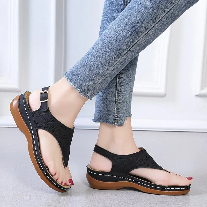 Women's wedge heel flip flop sandals with an adjustable buckle back strap in black.