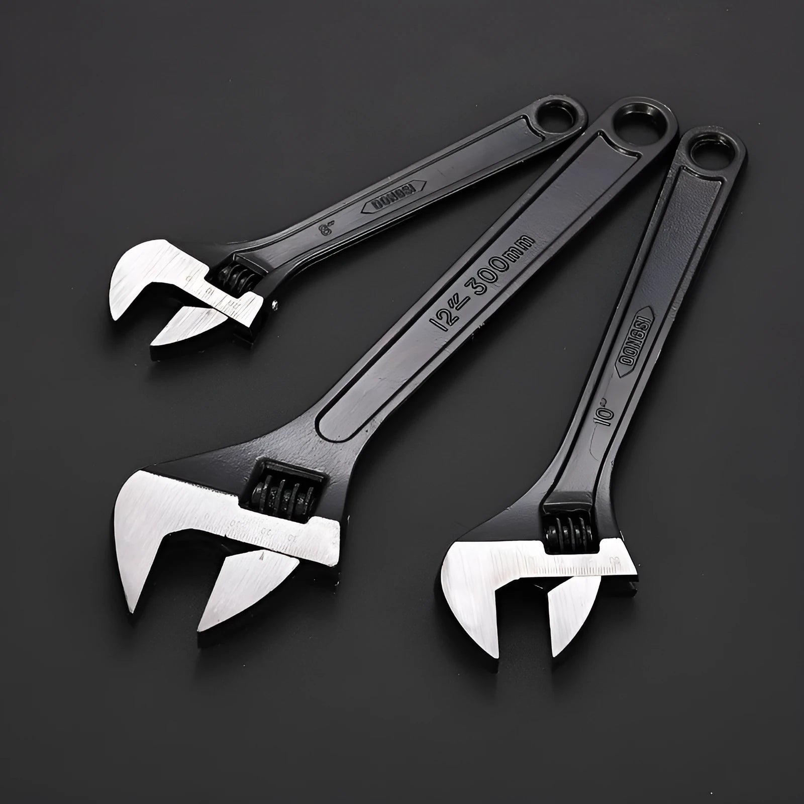Black stainless steel adjustable open-end wrench on a workbench, showing size markings and ergonomic handle.