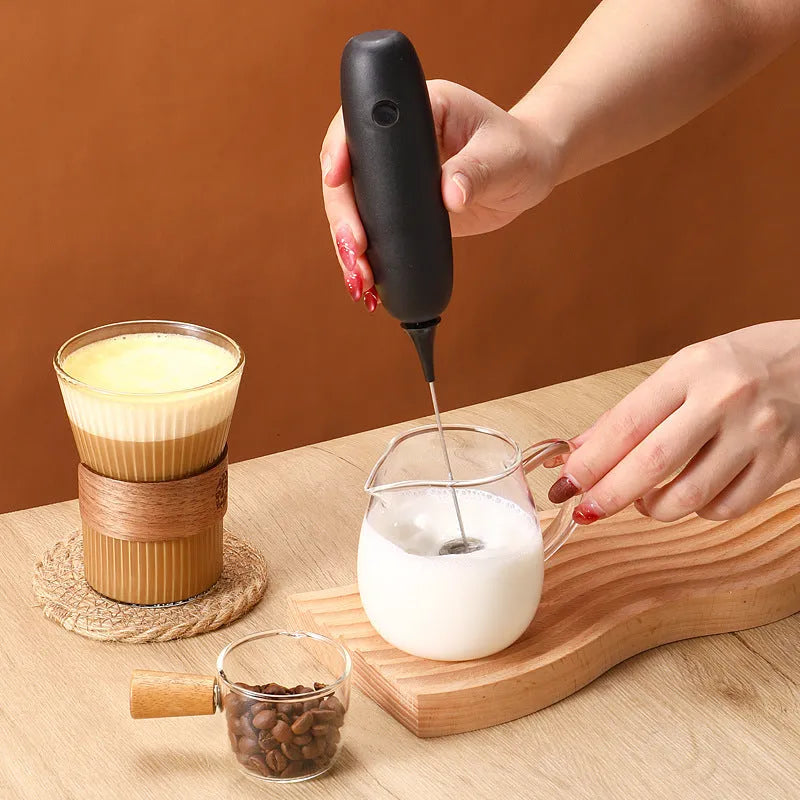 Handheld electric milk frother in black and white colours for making coffee and hot chocolate foam.