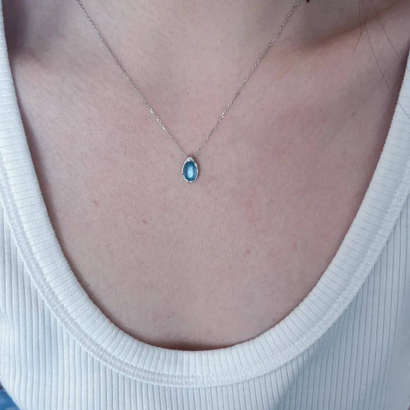 Navy blue geometric water drop pendant necklace on model showing adjustable cross chain design