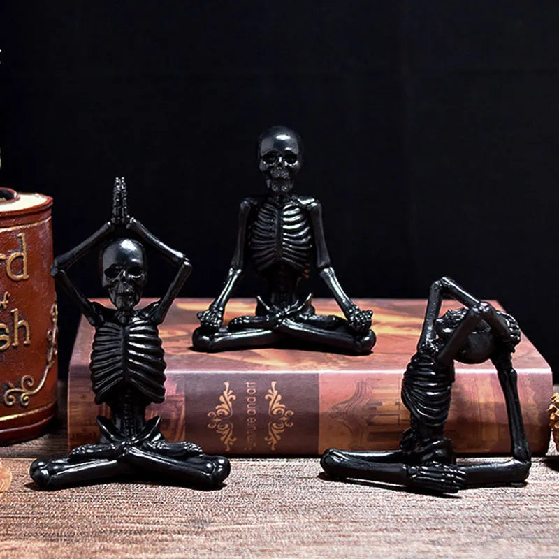 Detailed resin ornament of a yoga pose skeleton skull on a desktop, shown in black and white colour options.