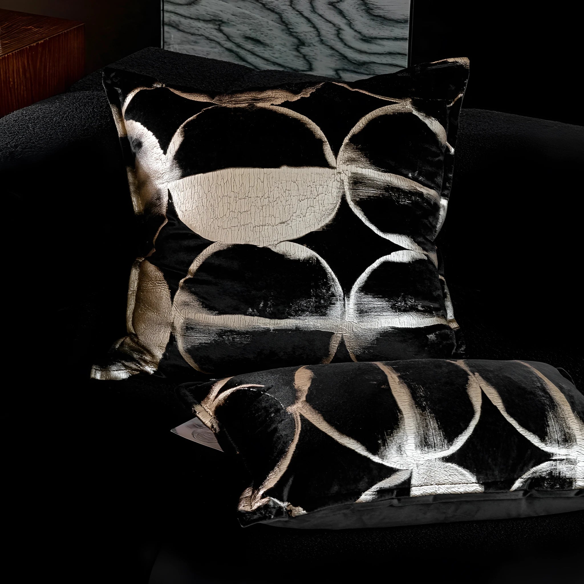 Black and gold abstract patterned decorative cushion on a sofa, available in three sizes with a removable cover.