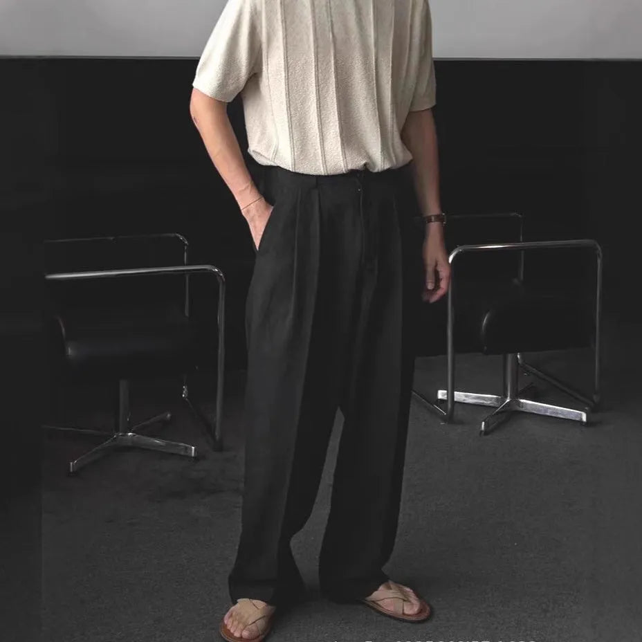 Man wearing apricot coloured loose wide-leg cotton linen trousers with a pencil leg opening.
